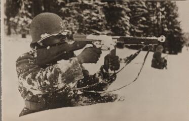 Soldat de la 1ère armée française, armé d'un pistolet mitrailleur Thompson, combattant dans la neige.