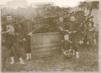 Section Hors-rang du 20e bataillon de chasseurs : vue des musiciens posant devant un panneau sur lequel on lit « Classe 1902, encore 68 [jours] et la fuite ». Le caporal Henri Thieriot est accroupi.