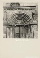 Saint-Ursanne - collégiale. – Vue rapprochée sur le portail et le fronton ; tympan avec le Christ entouré de saints Paul et Pierre, statues d'une Vierge à l'Enfant et de saint Ursanne.